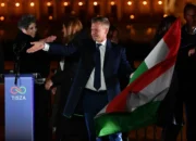 Peter Magyar, pemimpin partai konservatif pro-Eropa TISZA, mengibarkan bendera nasional di tepi sungai Danube di Hongaria, pada 12 April 2026. Foto: Ferenc Isza/AFP